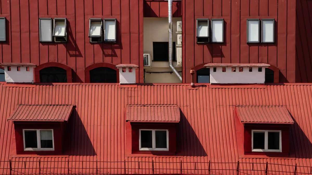 Red building facade featuring windows and air conditioning units, showcasing urban architecture.
